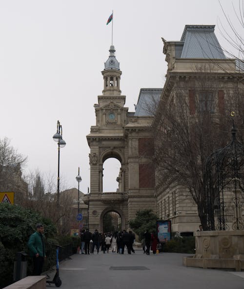 People walking in front of a large building with a clock tower