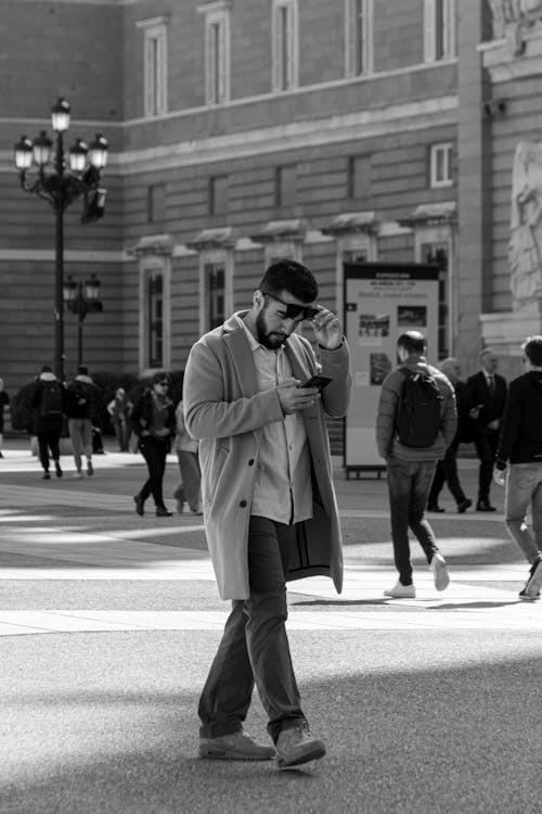 Free A man walking down a street with his phone Stock Photo