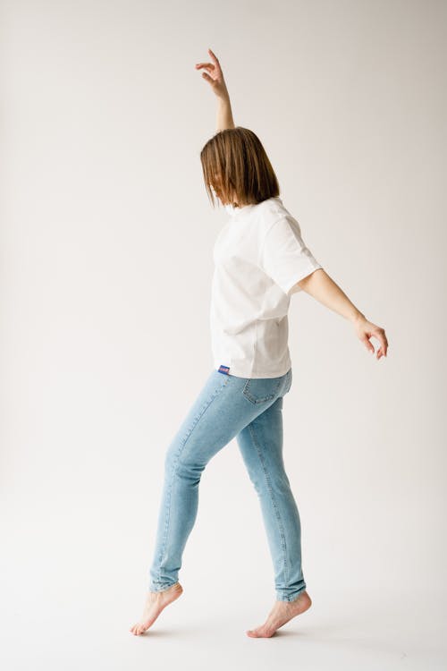 A woman in white shirt and blue jeans dancing