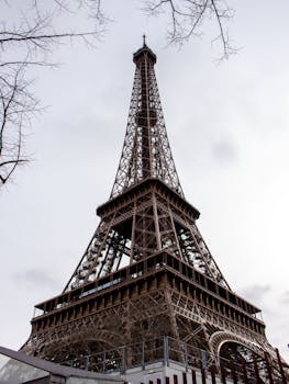 Upward view of Eiffel Tower in Paris, showcasing its iconic architecture.