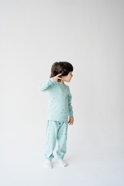 Free Kid wearing mint green pajamas posing against a white studio backdrop. Stock Photo