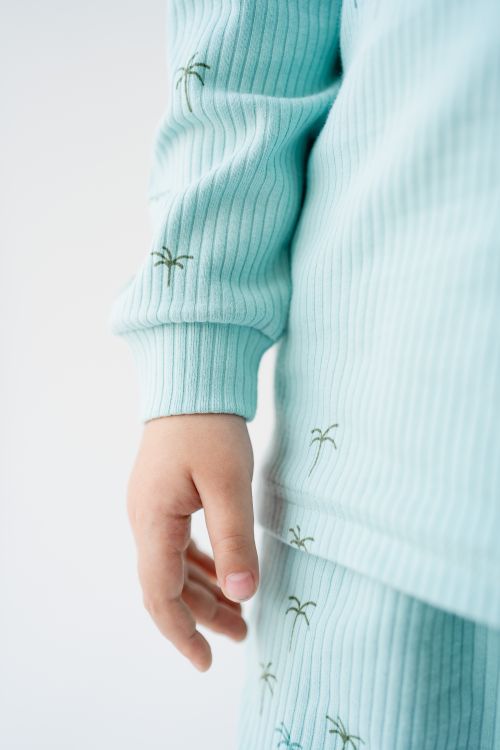 Free Detailed shot of a child's hand in light blue pajamas with palm tree prints, studio lighting. Stock Photo