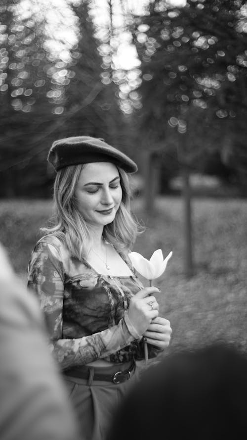 A woman in a beret holding a flower