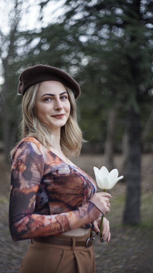A woman in a brown hat holding a flower