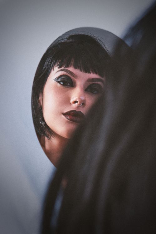 Free A captivating reflection of a woman with bold makeup in a round mirror. Stock Photo