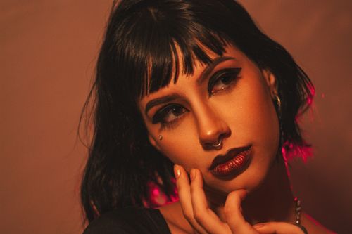 Free Portrait of a woman with piercing, dark makeup, and black hair in a studio setting. Stock Photo