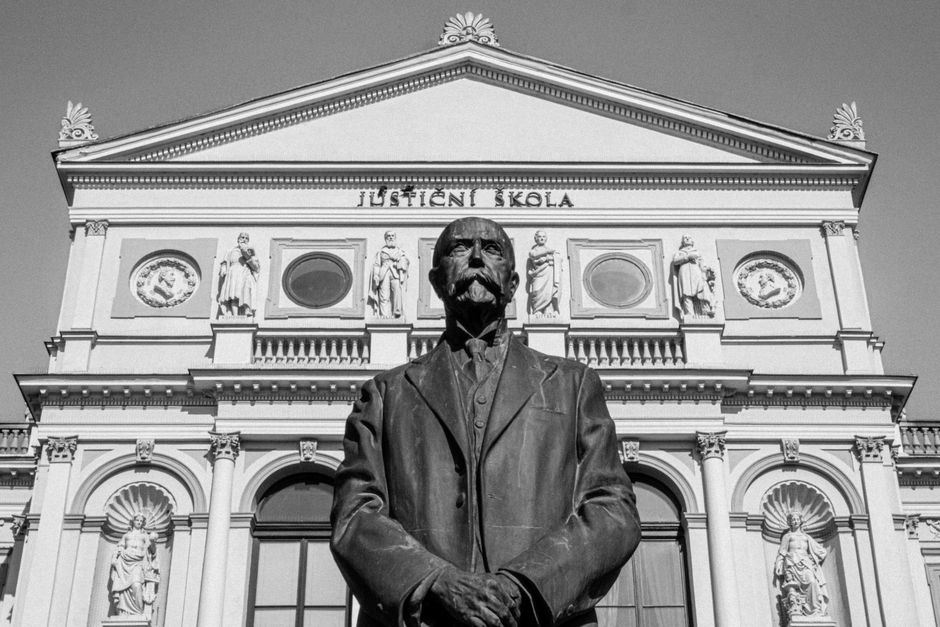 Black and white photo of a statue in front of a historic building facade.