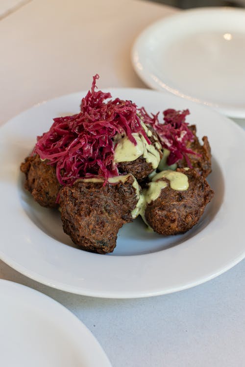 A plate of meatballs with red cabbage and sauce