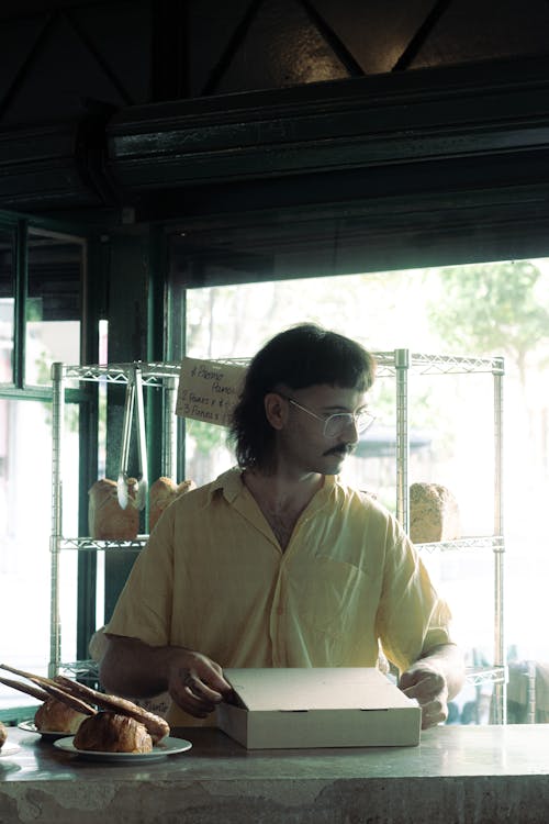 A man in a yellow shirt is standing in front of a counter