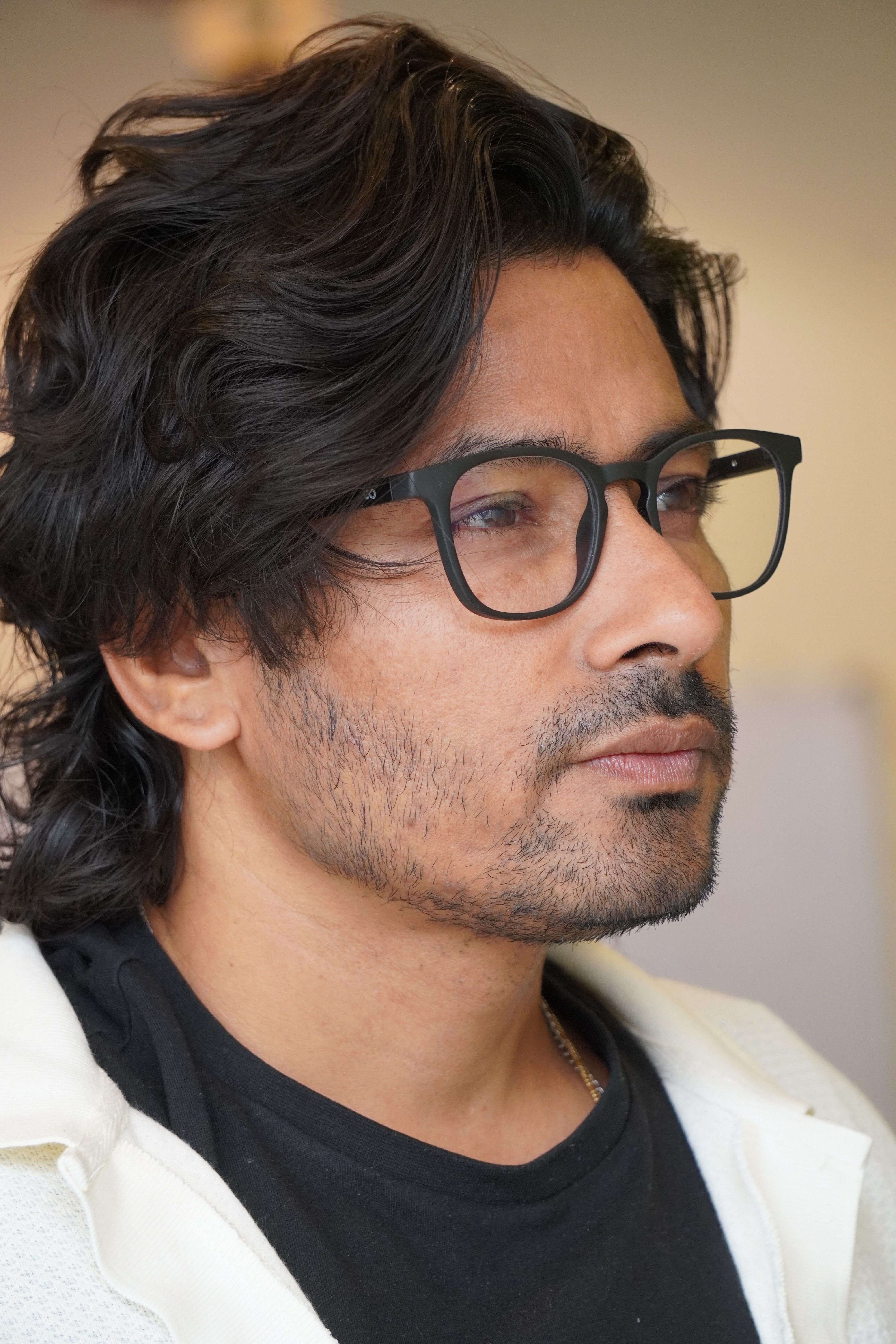 Close-up portrait of a thoughtful man wearing eyeglasses indoors.