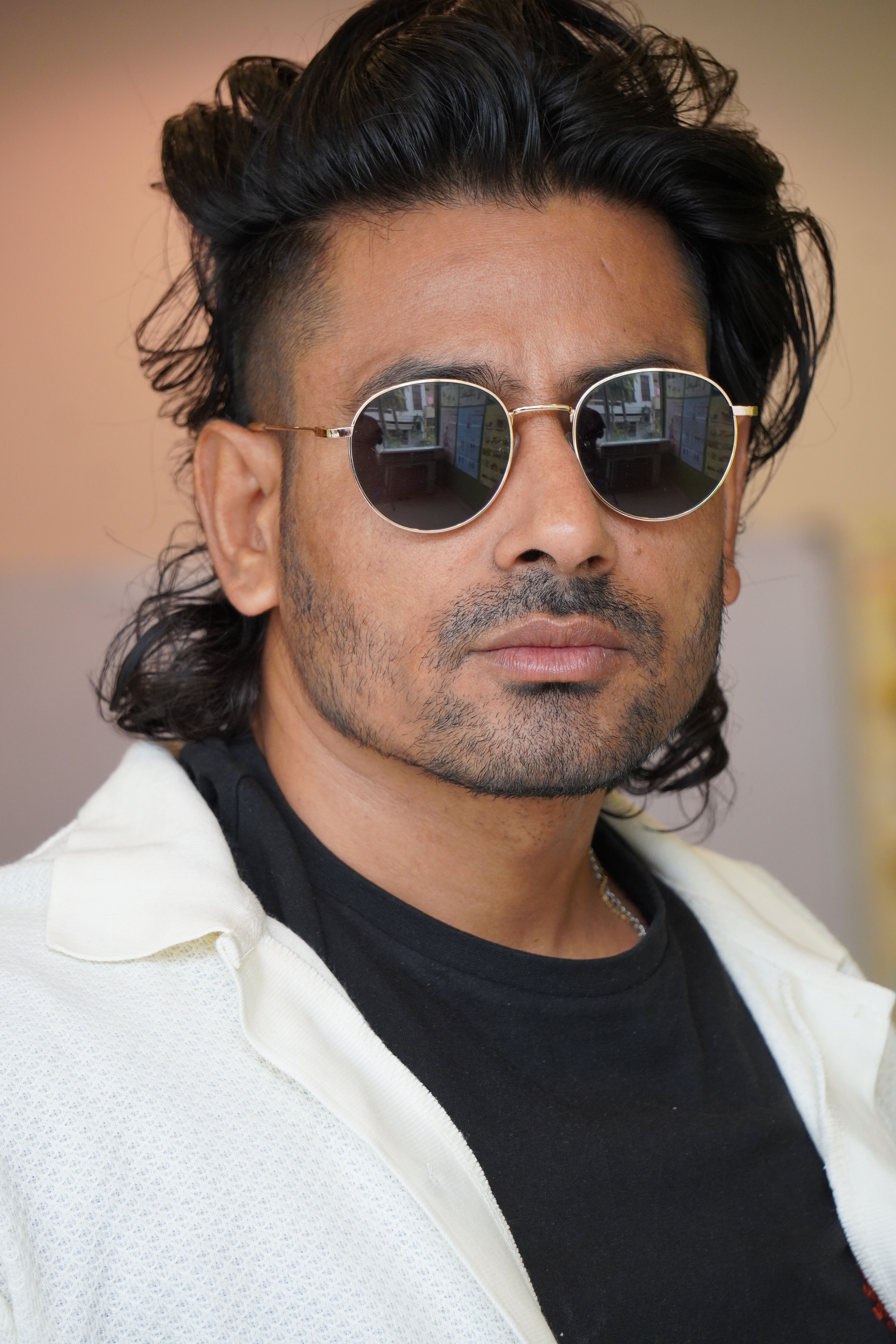 Portrait of a fashionable man wearing sunglasses and stubble, exuding a confident style.