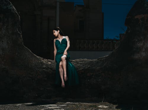A woman in a green dress sitting on a rock