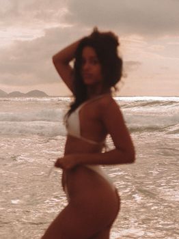 Blurred silhouette of a woman in swimsuit on a scenic beach during sunset.