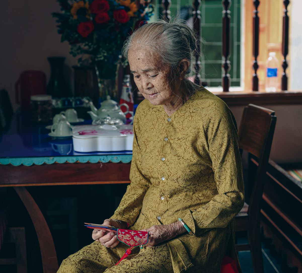 Elderly Malaysian woman seated in the room of her home where oxygen equipment is set up