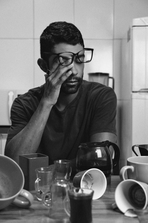 Free Black and white portrait of a tired man sitting at a kitchen table with coffee cups. Stock Photo