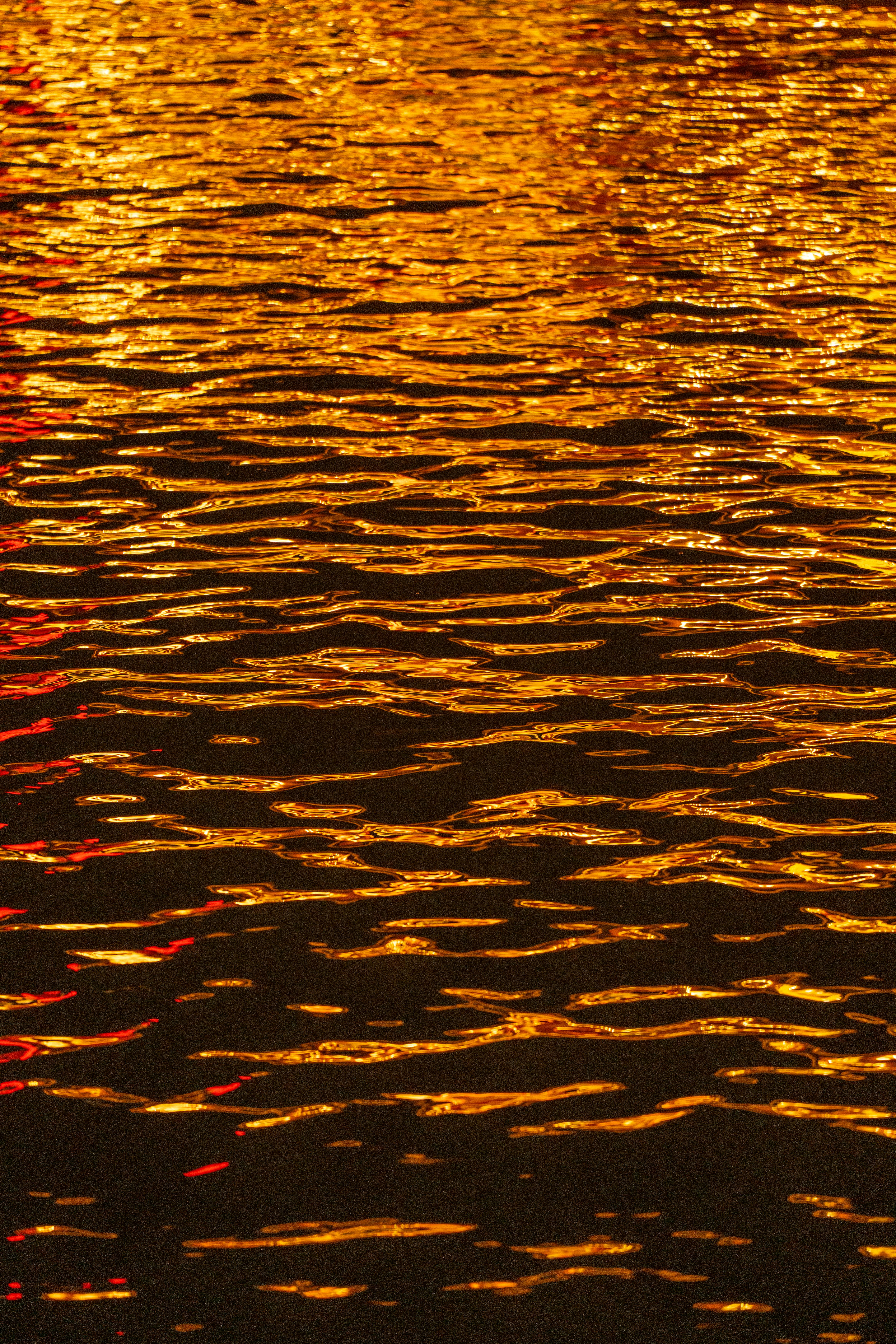 Captivating night reflection with golden ripples on water surface.
