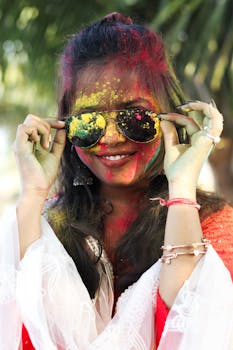 Smiling woman with vibrant colors on her face celebrating Holi outdoors in Patna, India.