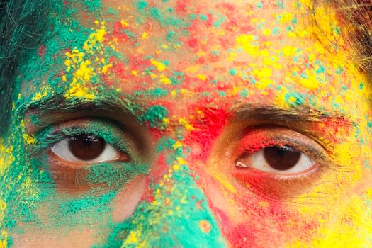 Close-up of a face covered with vibrant Holi festival colors.