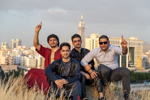 A group of friends smiling and posing in front of Makkah's skyline, capturing a joyful urban moment.