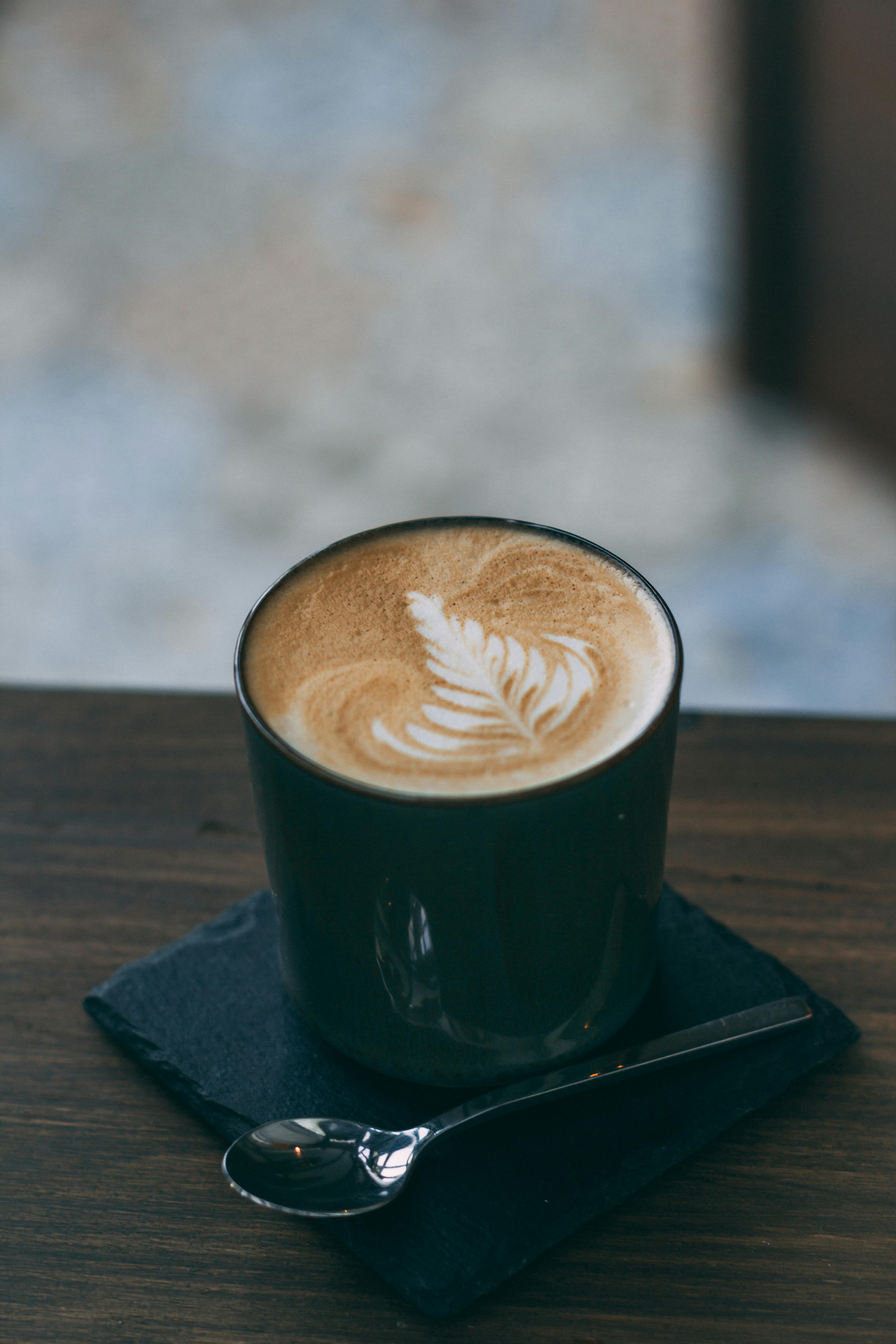 Person Holding Cup of Coffees on Table · Free Stock Photo