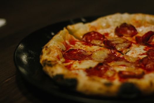 Close-up of hot pepperoni pizza on a rustic plate, showcasing melted cheese and crispy crust.