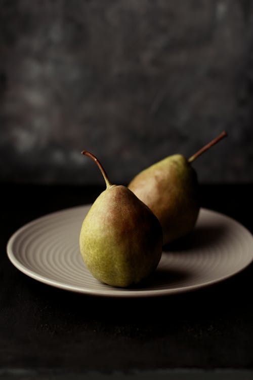 Two Oval Green Fruits on White Ceramic Plate