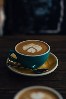 木桌上绿松石杯中的拿铁艺术特写，非常适合咖啡馆主题的图像