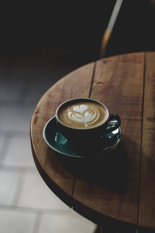 Free Artistic cappuccino on wooden table with heart latte art at dawn. Stock Photo