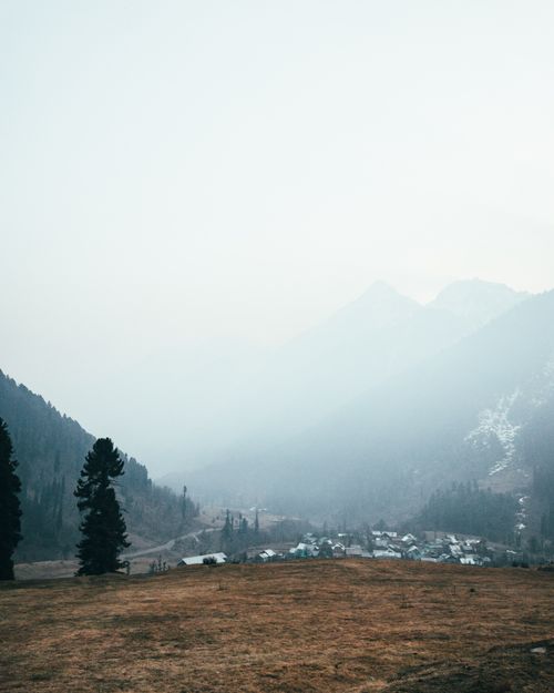 Free Serene misty landscape of Pahalgam with mountains and village in early morning light. Stock Photo