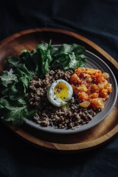 深色桌子上有一道乡村菜肴，特色是蔬菜、荷包蛋、碎肉和西红柿