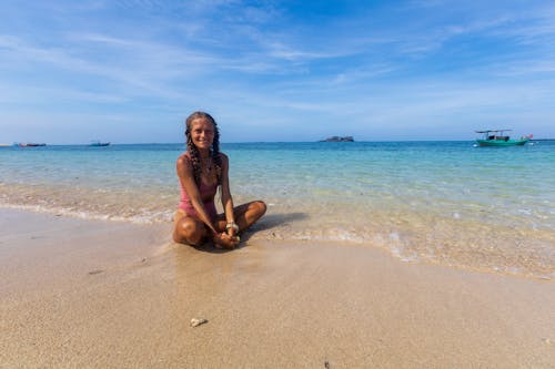 Free A woman sitting on the beach with her legs crossed Stock Photo