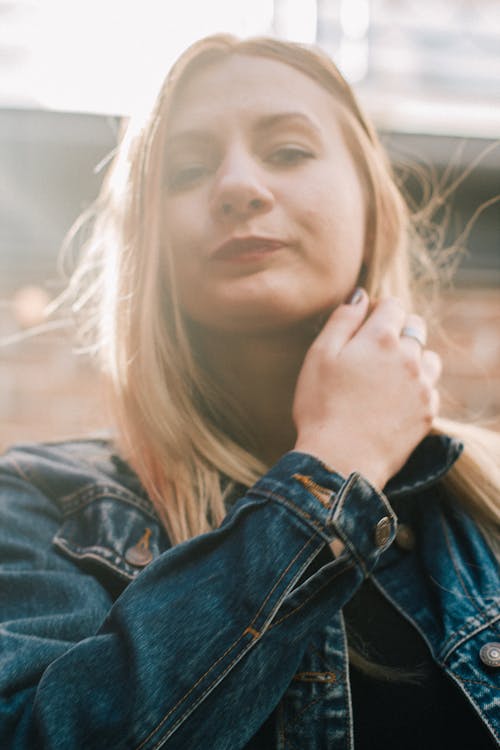 Woman in Denim Jacket with Hand on Neck