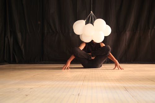Человек в позе йоги с воздушными шарами