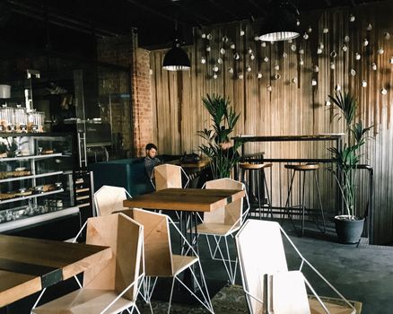 A stylish modern cafe featuring geometric chairs, plants, and warm lighting, perfect for a relaxed atmosphere.