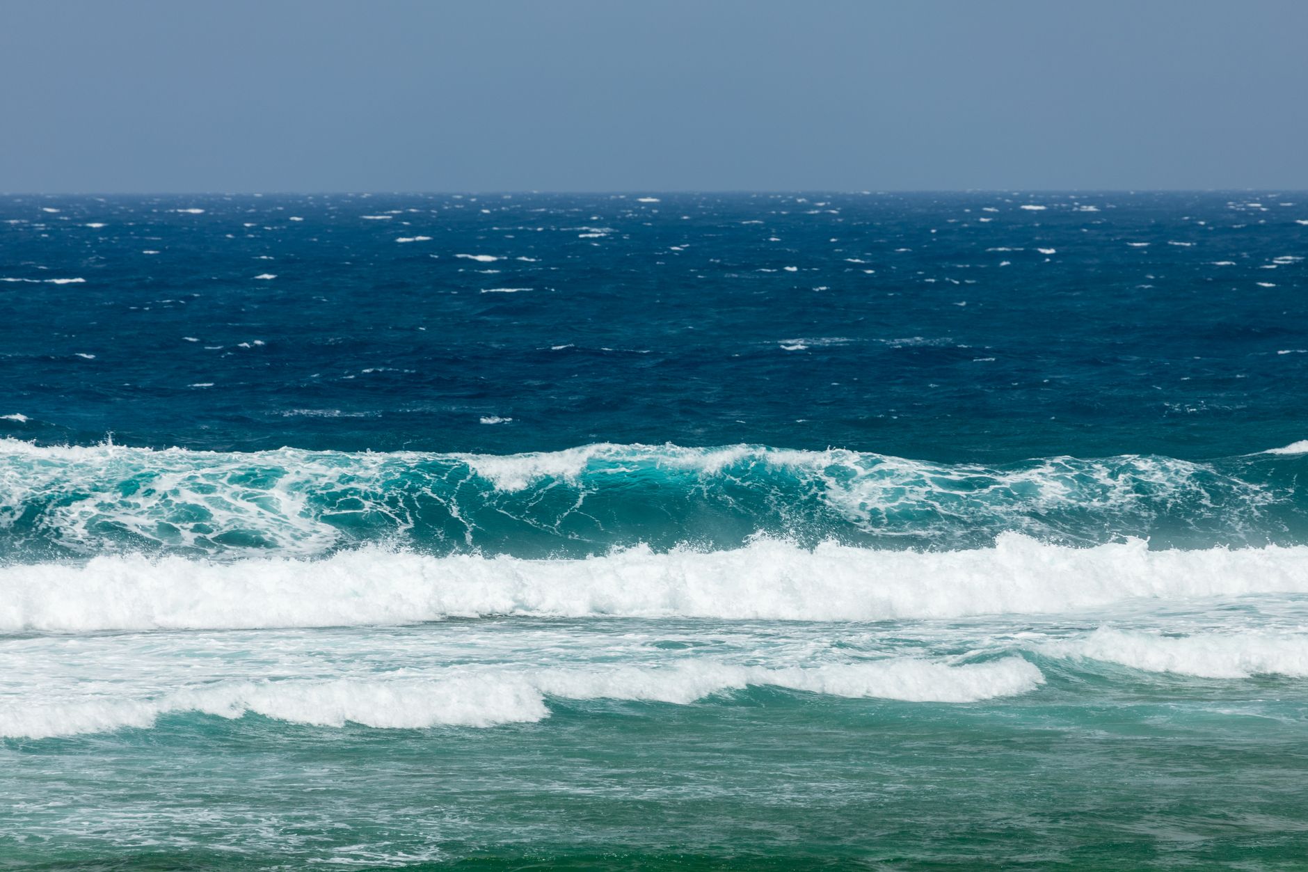 Dynamic ocean waves crashing on the shore, showcasing vibrant blue and teal hues.