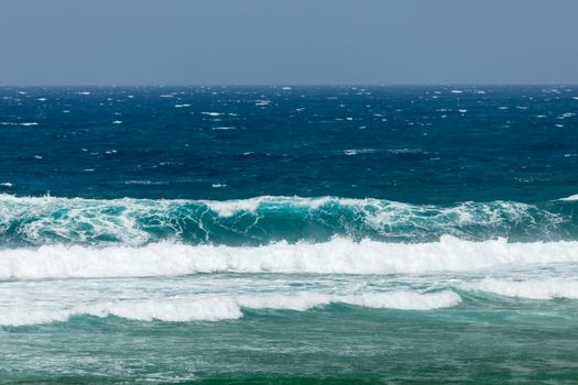 Dynamic ocean waves crashing on the shore, showcasing vibrant blue and teal hues.