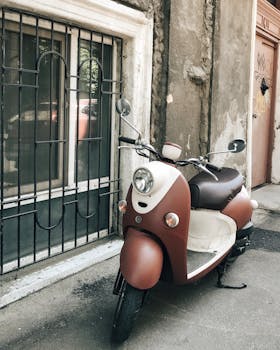 一辆经典的摩托车停靠在乡村一堵带有栅栏窗户的墙边，非常适合城市怀旧主题