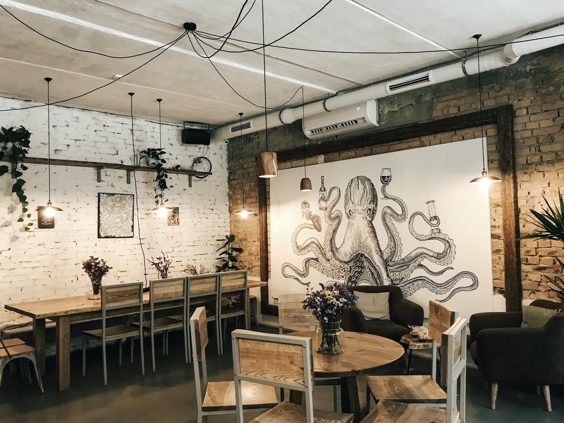 Charming restaurant interior with wooden furniture and octopus mural art, offering a cozy and artistic atmosphere.