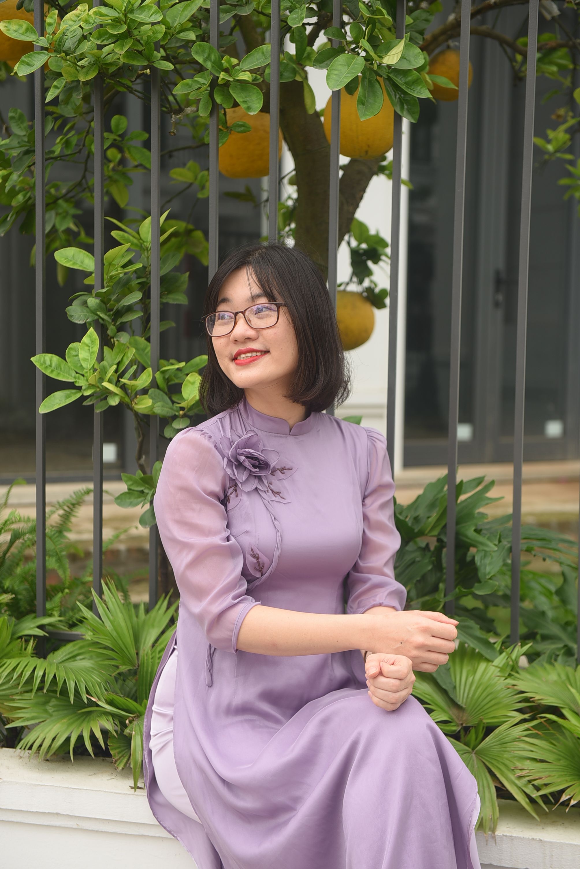 Asian woman in a lilac dress enjoying a serene outdoor setting.