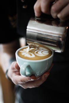Close-up of a barista making intricate latte art in a cozy coffee shop setting.