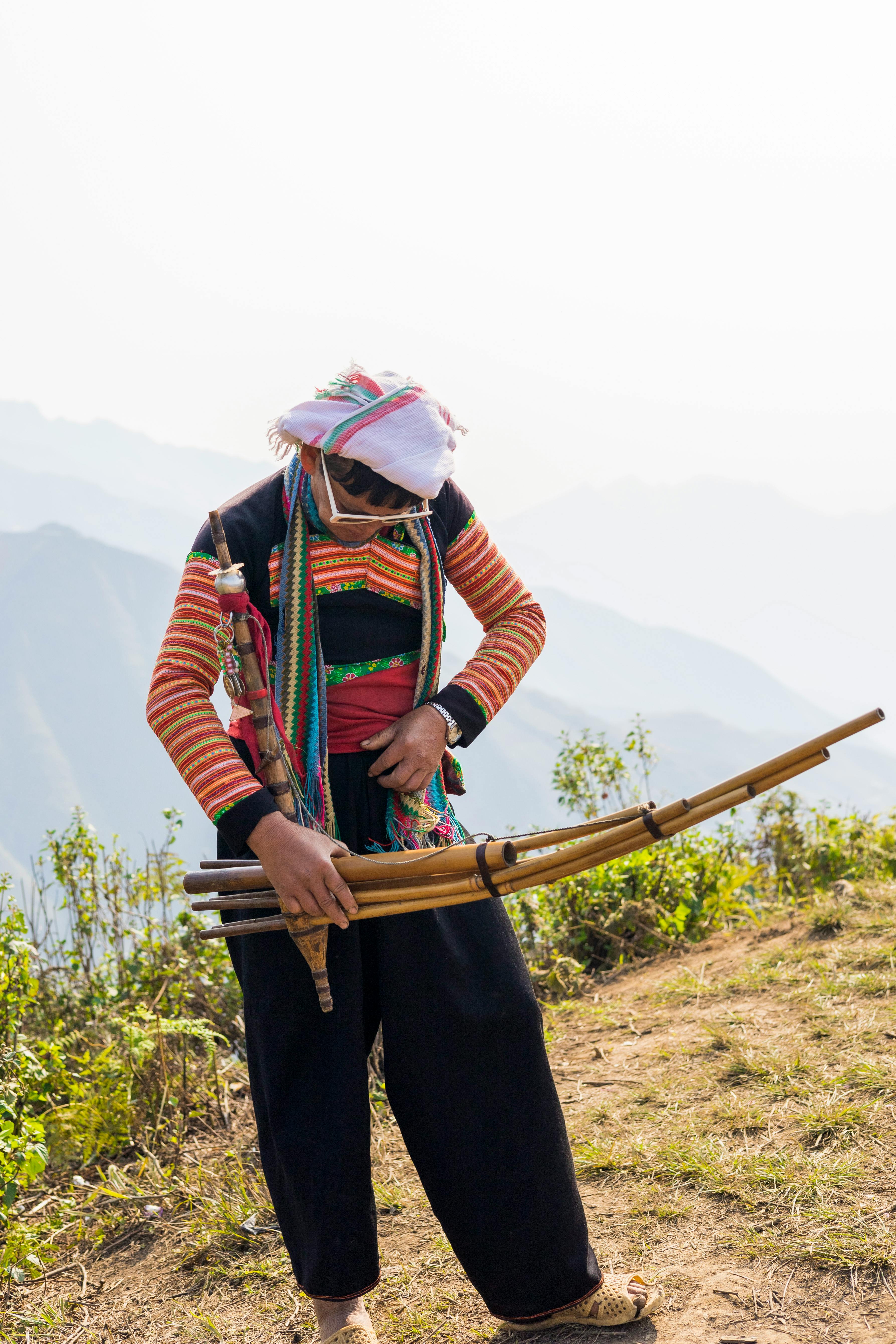 A man in traditional attire plays a unique musical instrument in rural Sơn La, Vietnam.