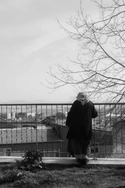 Back View of a Woman Standing by the Railing with View of a City 