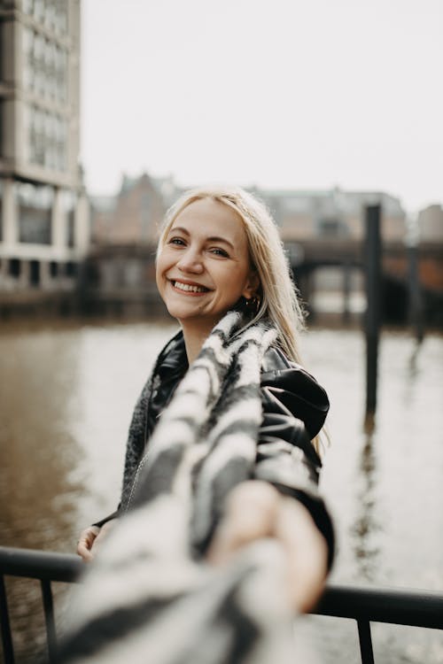 Blonde Wearing a Scarf, Smiling on an Urban Footbridge
