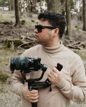 Man with camera in forest, capturing nature's beauty. Outdoors setting.