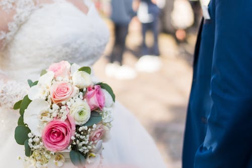 A bride and groom are holding their wedding bouquet