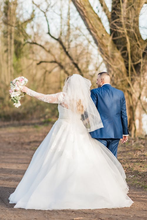 A bride and groom walking down a dirt road