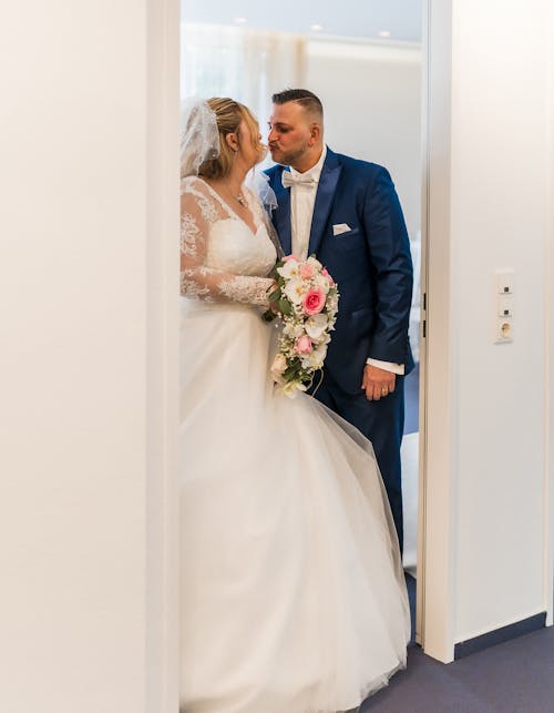 A bride and groom kiss in the doorway of their wedding