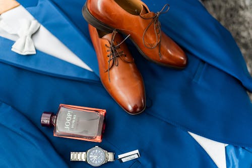 A man's suit, shoes, and watch are on a blue table
