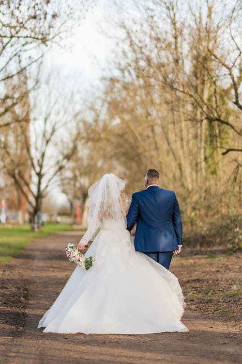 A bride and groom walking down a dirt road