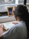 Brunette Reading a Book by a Window